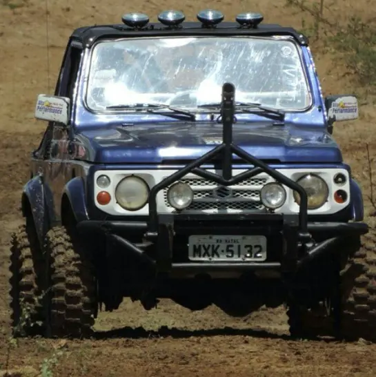 Jipe azul equipado com pneus Cross em pista de terra