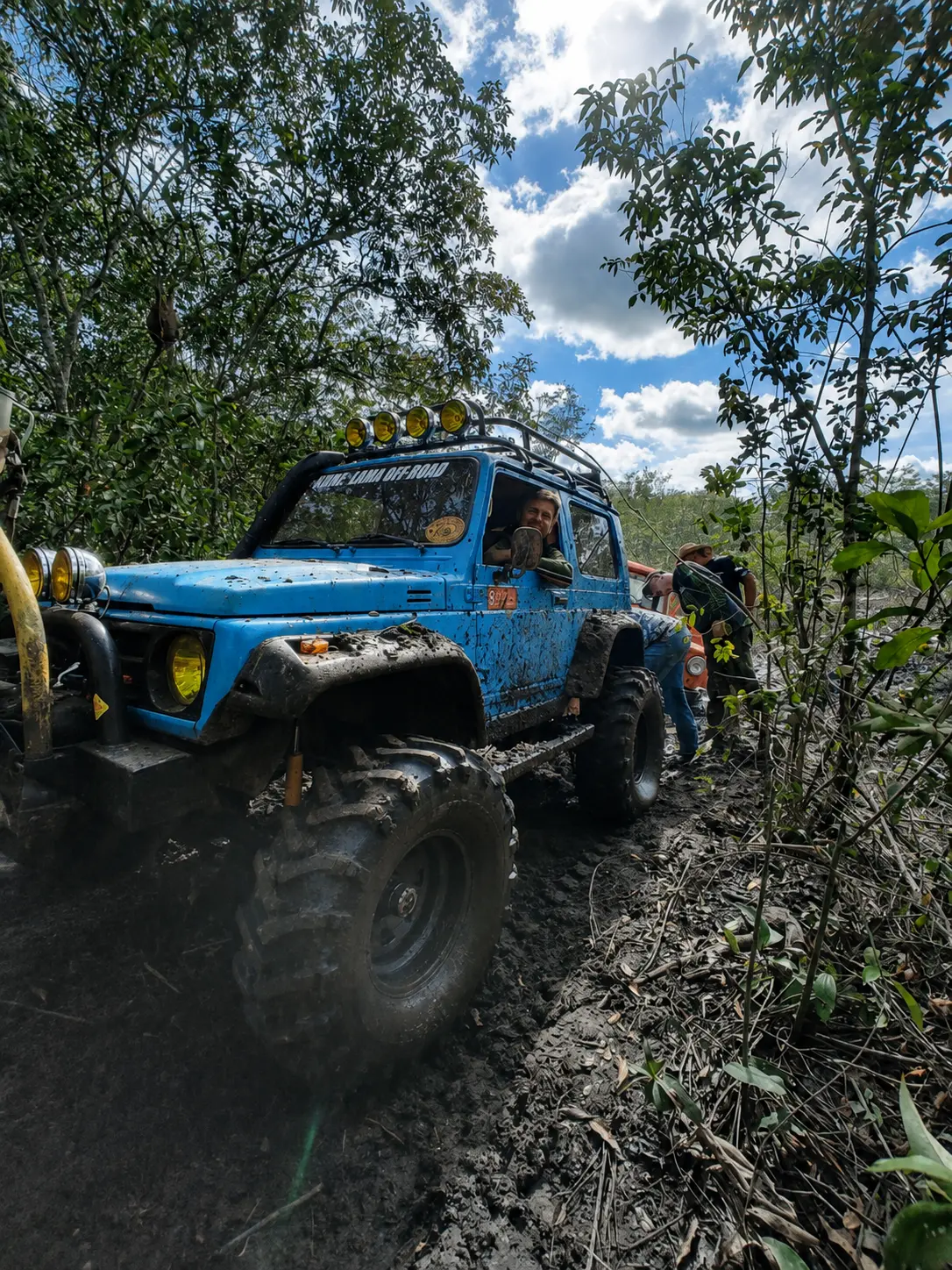 Veículo azul equipado com pneus Dardara em trilha com lama