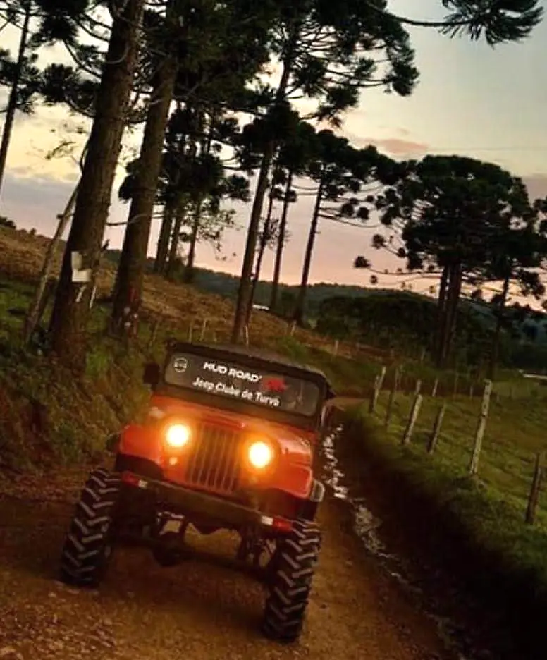 Jeep vermelho equipado com pneus Dardara em estrada rural ao entardecer