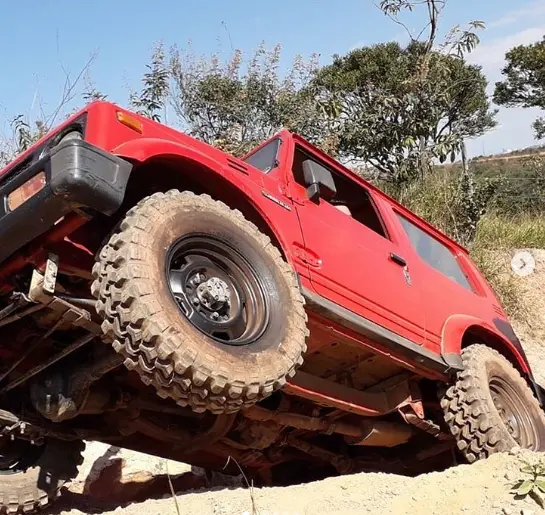 Veículo 4x4 vermelho equipado com pneus Mud em trilha