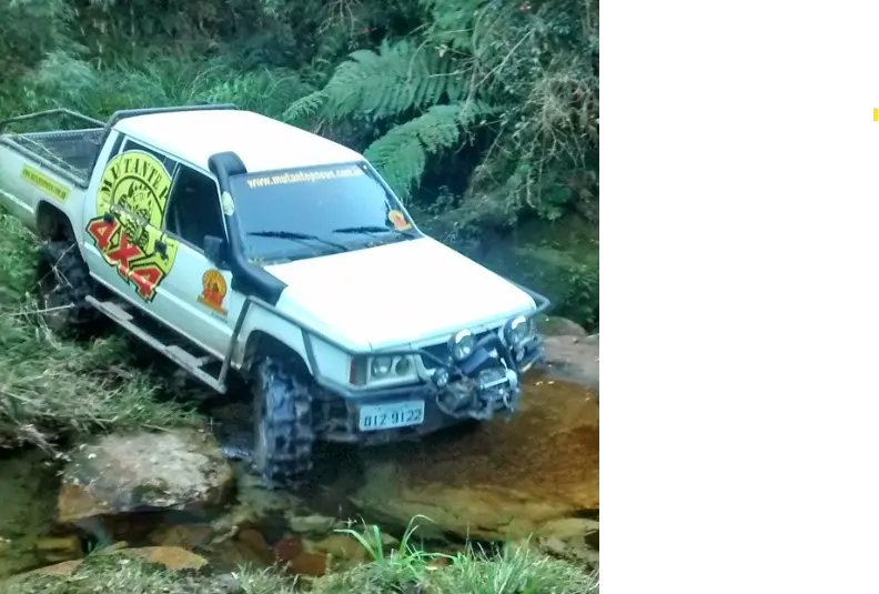 Caminhonete branca equipada com pneus Vírus atravessando riacho
